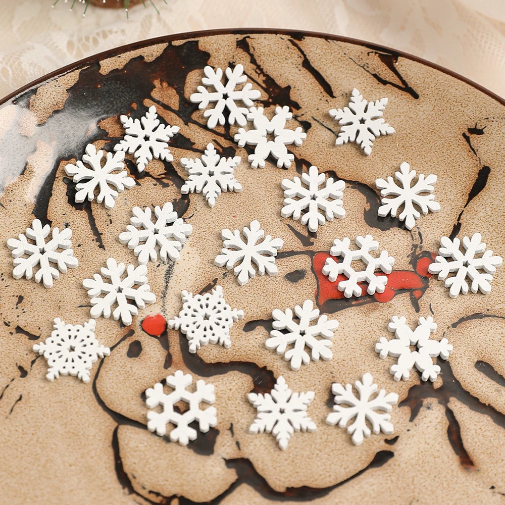 White wood snowflake ornaments in assorted designs are scattered across a tan decorative plate with dark branches and red accents.