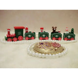 A green and red Christmas train decoration with snowflake details stands behind white beads and a gold floral ornament.