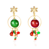 Snowflake drop earrings with gold-tone rings, green and red glitter balls, bells and striped candy cane charms appear against a white background.