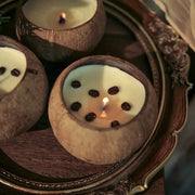 Coconut shell candles topped with coffee beans, lit on an ornate tray