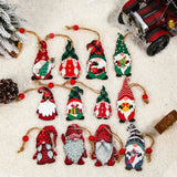 Twelve colorful wooden gnome Christmas ornaments rest on artificial snow beside a pinecone, miniature snowy tree, and red toy vehicle.