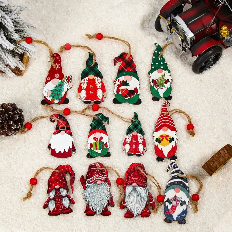 Twelve colorful wooden gnome Christmas ornaments rest on artificial snow beside a pinecone, miniature snowy tree, and red toy vehicle.