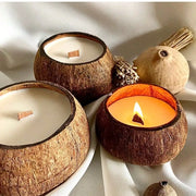 Three coconut wax candles in coconut shells, one lit with a warm glow