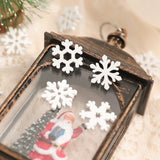 White wood snowflake ornaments decorate a distressed dark lantern with a Santa figurine visible behind the glass.