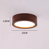 A flush-mount circular ceiling light fixture with a dark brown metal frame and a glowing white diffuser, shown with dimension lines indicating a height of 4.8CM and a diameter of 23CM.
