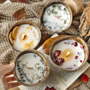 Four coconut wax candles in coconut shells with dried orange, lavender and rose toppings