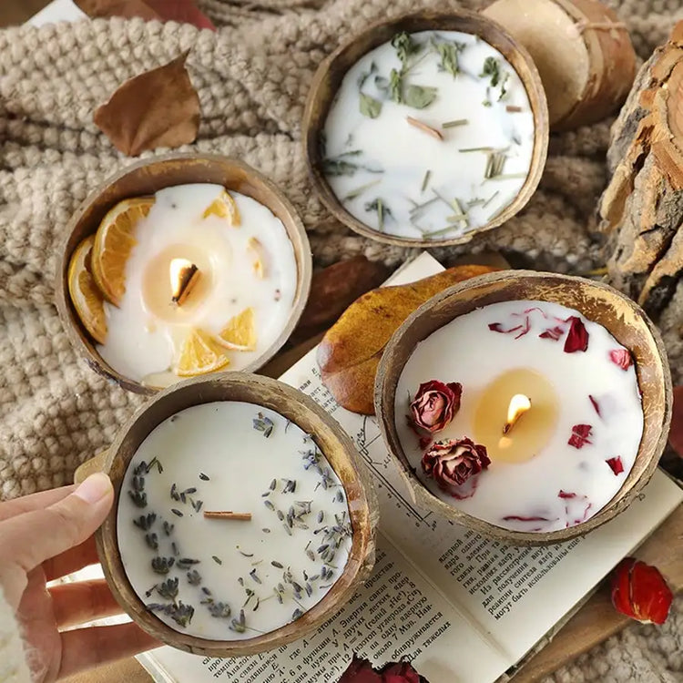 Four coconut wax candles in coconut shells with dried orange, lavender and rose toppings