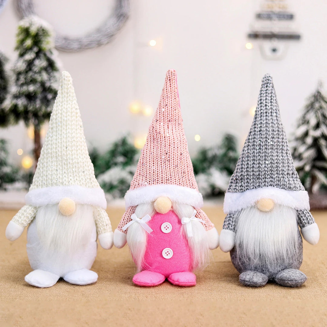 White, pink, and gray Christmas gnomes stand on burlap, with white braids and two buttons on the pink gnome.