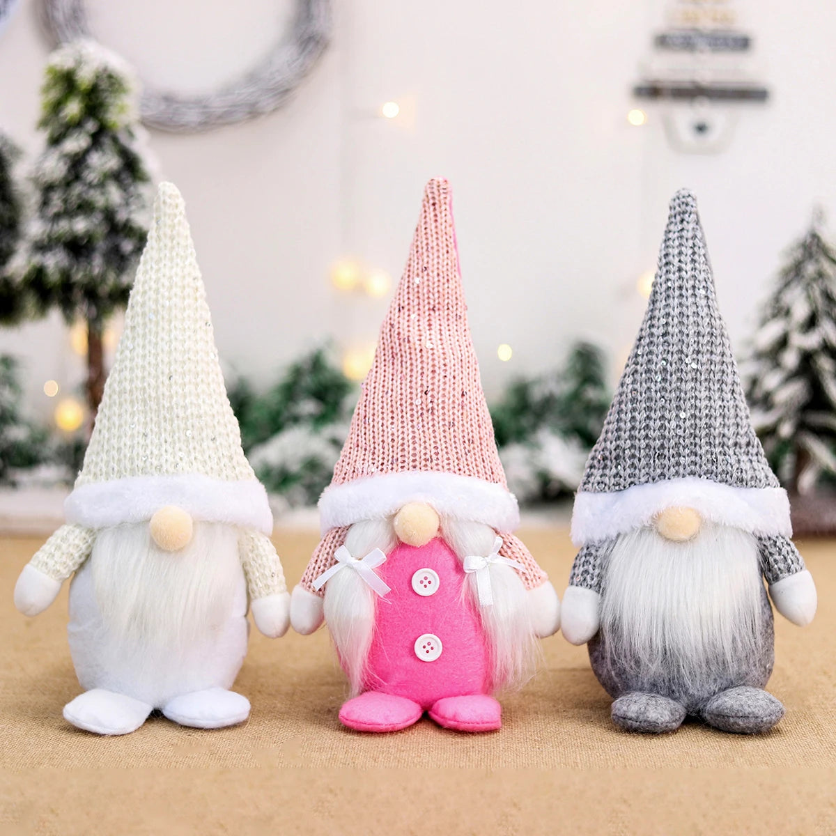 White, pink, and gray Christmas gnomes stand on burlap, with white braids and two buttons on the pink gnome.