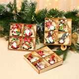 Wooden gnome Christmas ornaments with red and white beads sit in three divided boxes among evergreen branches and string lights.