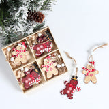 Tan and brown gingerbread Christmas ornaments with striped scarves sit inside and beside a divided box near snowy evergreen branches.