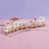 White Christmas train decoration with gold wheels and three connected carriages on pink, labeled 19.5 cm long, 4.6 cm high, and 3 cm wide.