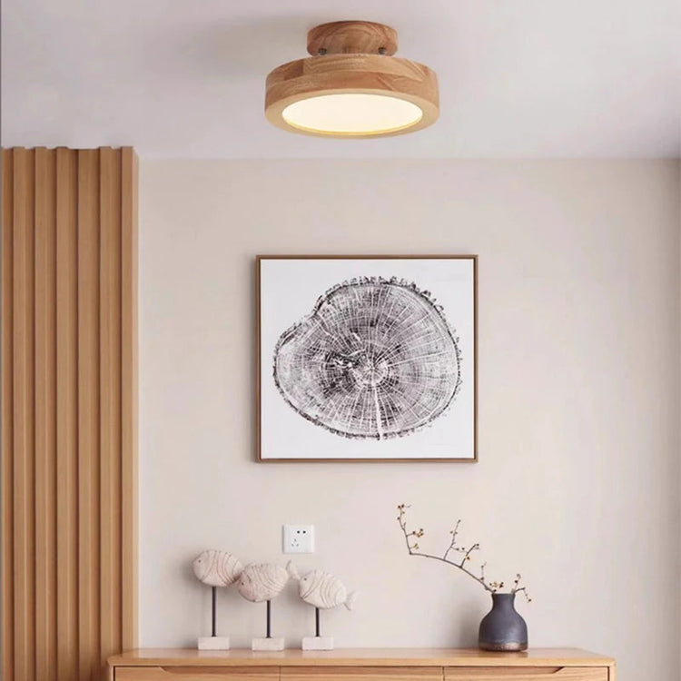 Wood flush mount ceiling light near a wood dresser with framed wall art and ceramic fish figurines