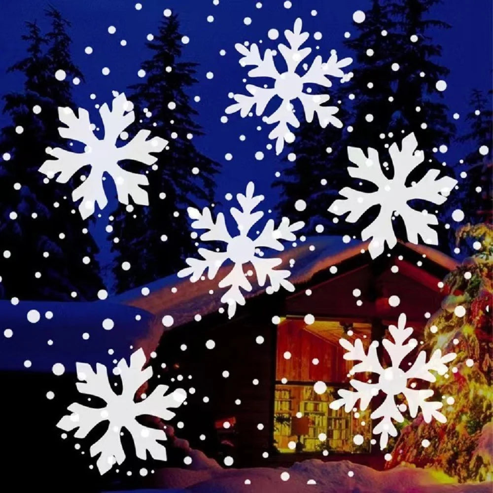 White snowflake and dot patterns from a light projector appear over a snowy cabin scene with evergreen trees and Christmas lights.