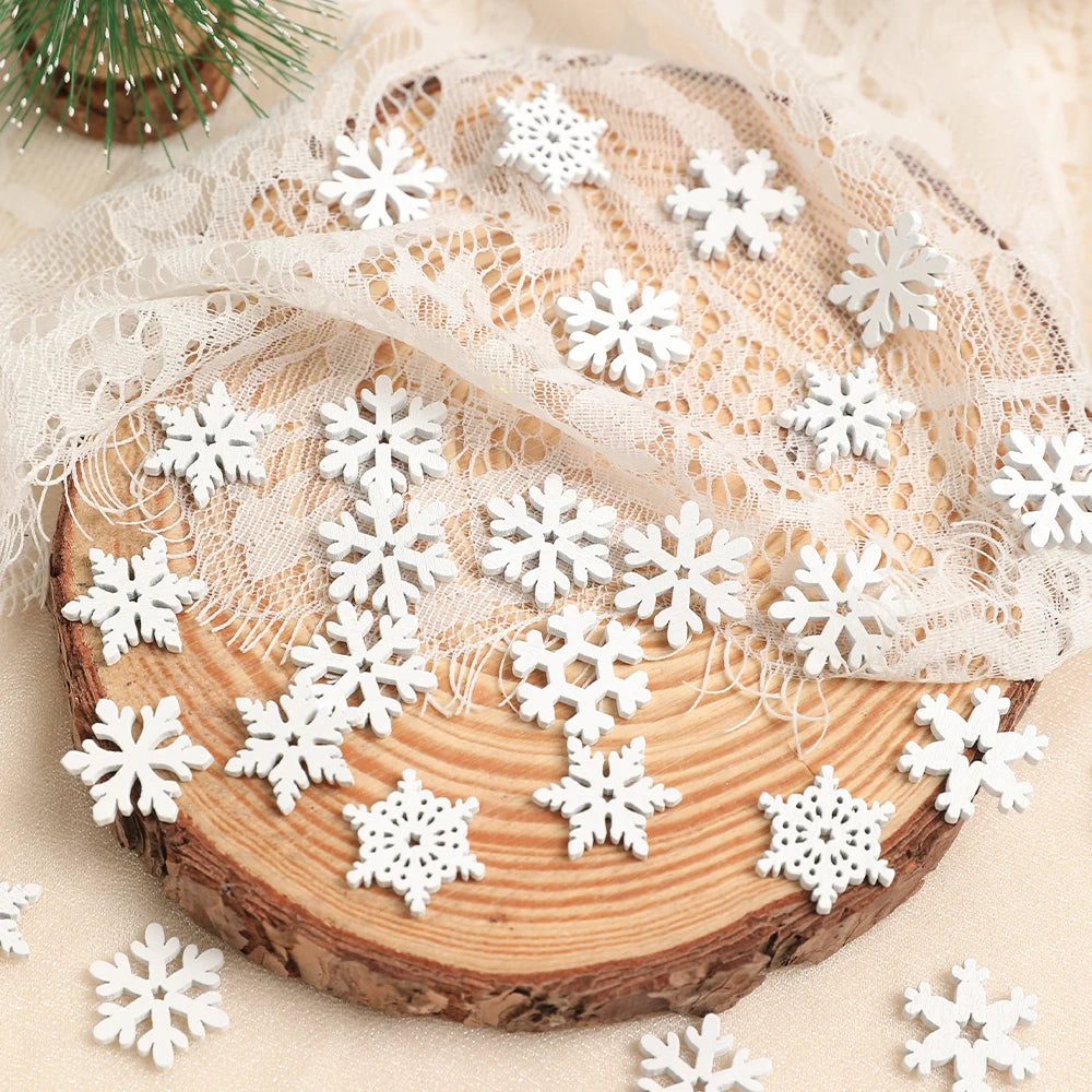 White wood snowflake ornaments spread across cream lace and a bark-edged wood slice beside a miniature green tree.