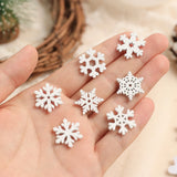 Seven white wood snowflake ornaments in different patterns rest in an open hand against a softly blurred cream background.