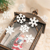 Five white wood snowflake ornaments decorate a dark lantern containing a Santa figurine and miniature Christmas tree.