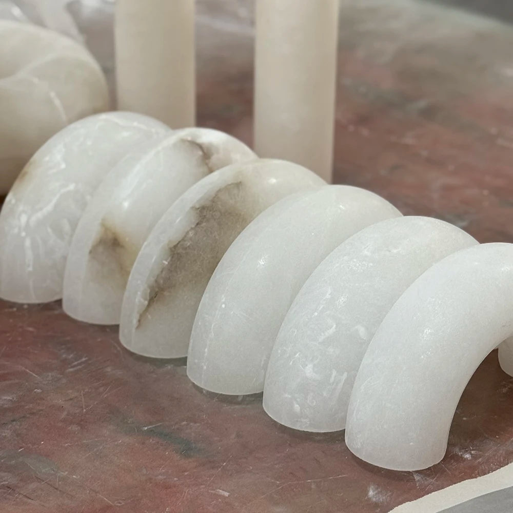 Pendant light alabaster material detail showing curved white stone pieces with gray veining arranged on a workbench.
