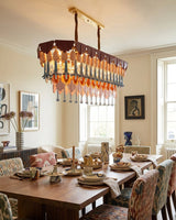 Dining room with a modern chandelier, wooden table, and chairs.