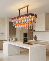 Modern kitchen with a colorful chandelier hanging above a marble island.