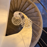 Globe pendant light grouping with illuminated metal lattice frames hangs through the center of a curved staircase.