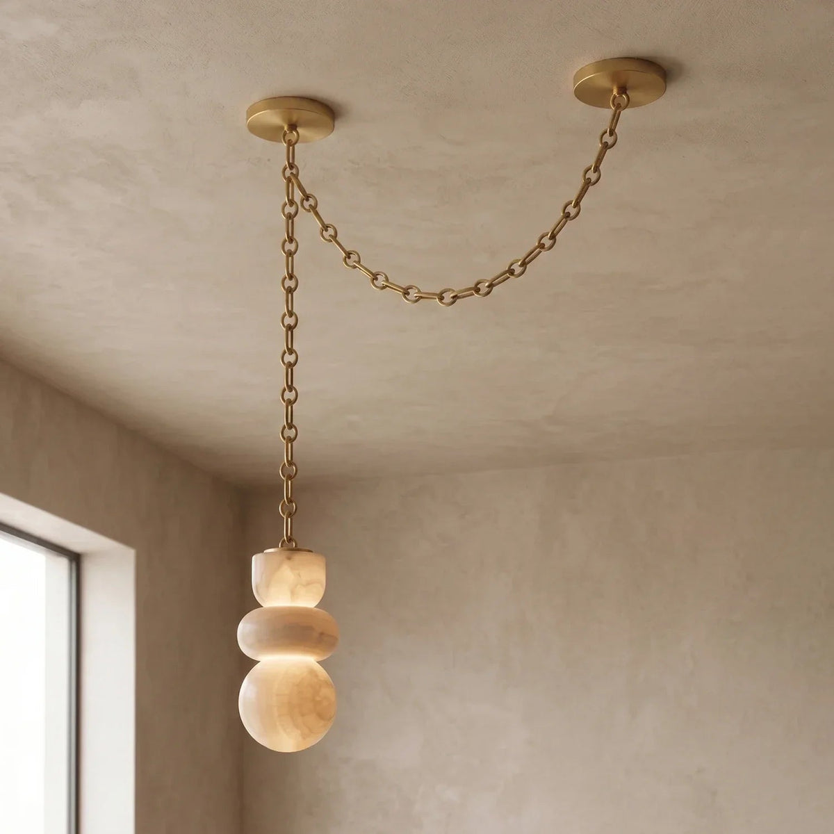 An alabaster chandelier hangs beside a window, with a gold-toned chain draped between two ceiling mounts.