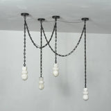 Front view of an unlit chandelier with four sculpted white alabaster shades, draped black chains, and round black ceiling mounts.