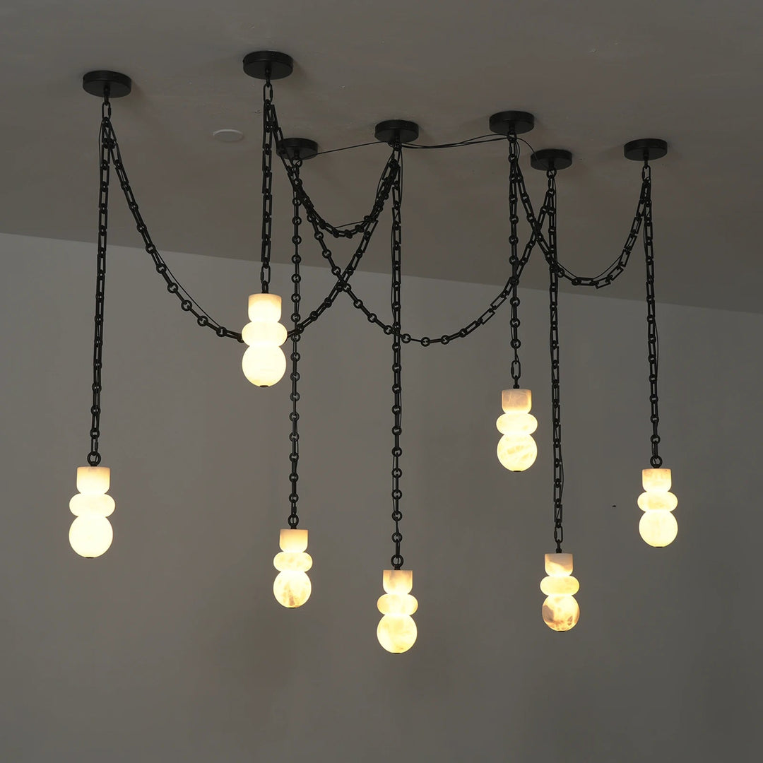A modern industrial-style chandelier with multiple black chain drops and stacked frosted glass bulbs, shown illuminated against a plain ceiling.