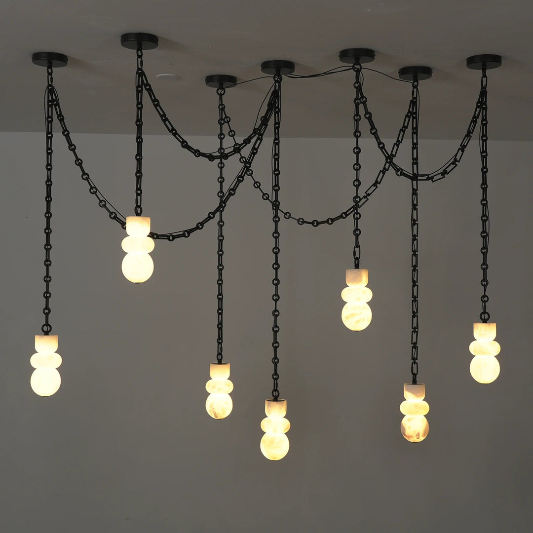 A multi-light pendant chandelier with black metal chains and spherical glass shades, shown hanging against a plain light gray wall.