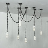 A modern multi-light chandelier with black metal chains and spherical white glass shades, suspended from a ceiling in a minimalist room.