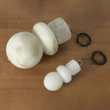 Large and small alabaster chandelier shades in stacked stone shapes with coiled cords on a wooden table.