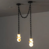 Alabaster chandelier has two glowing drops at different heights, suspended from black chains against a gray wall.