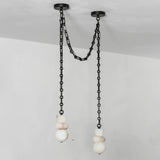 Alabaster chandelier with two white sculpted shades hanging at different heights from black swag chains against a pale wall.