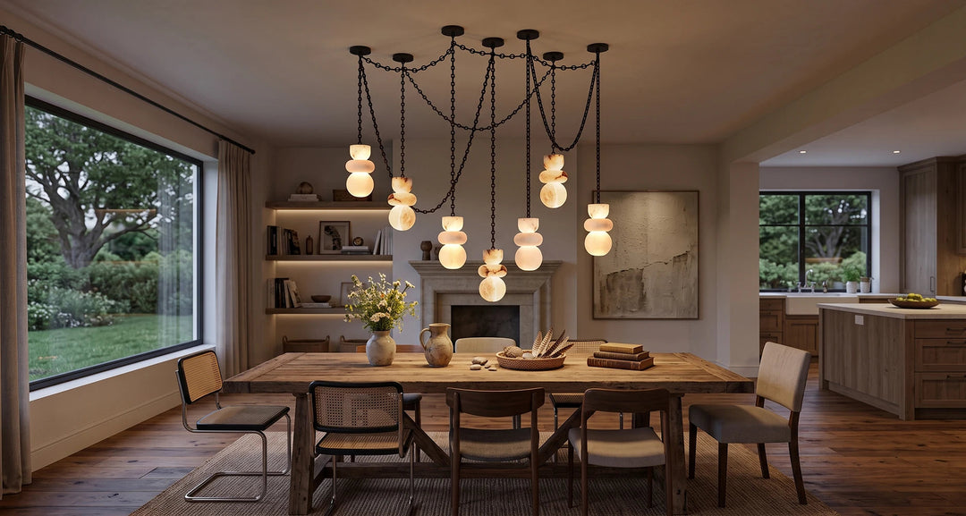 A modern multi-light pendant chandelier with multiple black chains and glowing frosted glass globes, hanging over a wooden dining table in a warm, contemporary dining room.