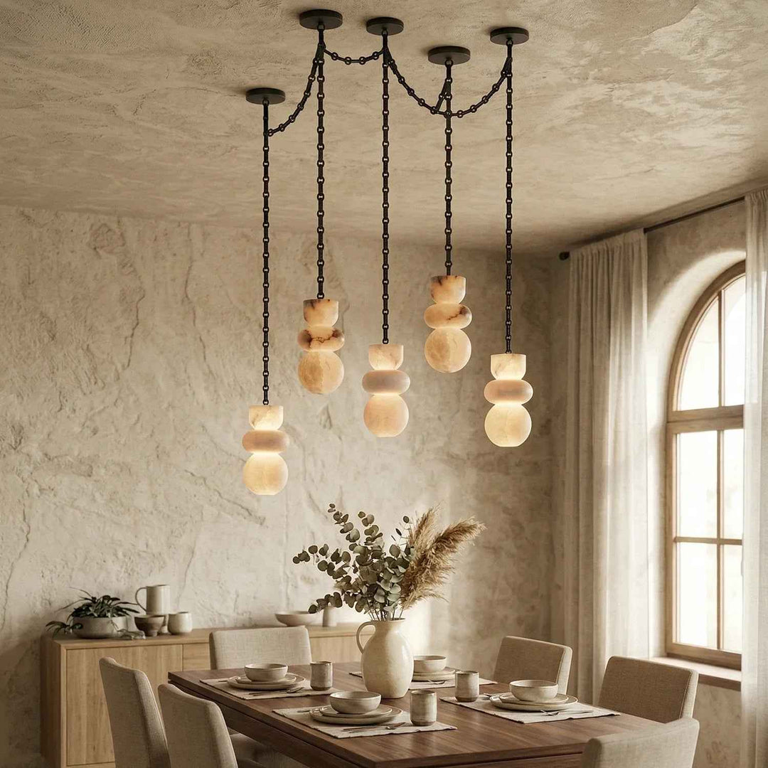A modern multi-light pendant chandelier with stacked organic-shaped frosted glass shades hanging from a black metal frame in a rustic dining room.