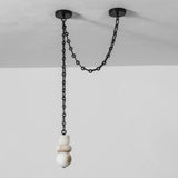 Unlit white alabaster chandelier hangs beneath a black chain looped between two ceiling mounts against a pale wall.