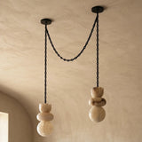 Unlit alabaster chandelier with two cream stone drops and draped black chains beneath a textured beige ceiling.
