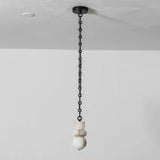 Unlit chandelier with stacked white alabaster shapes hangs from a straight black chain against a pale wall.