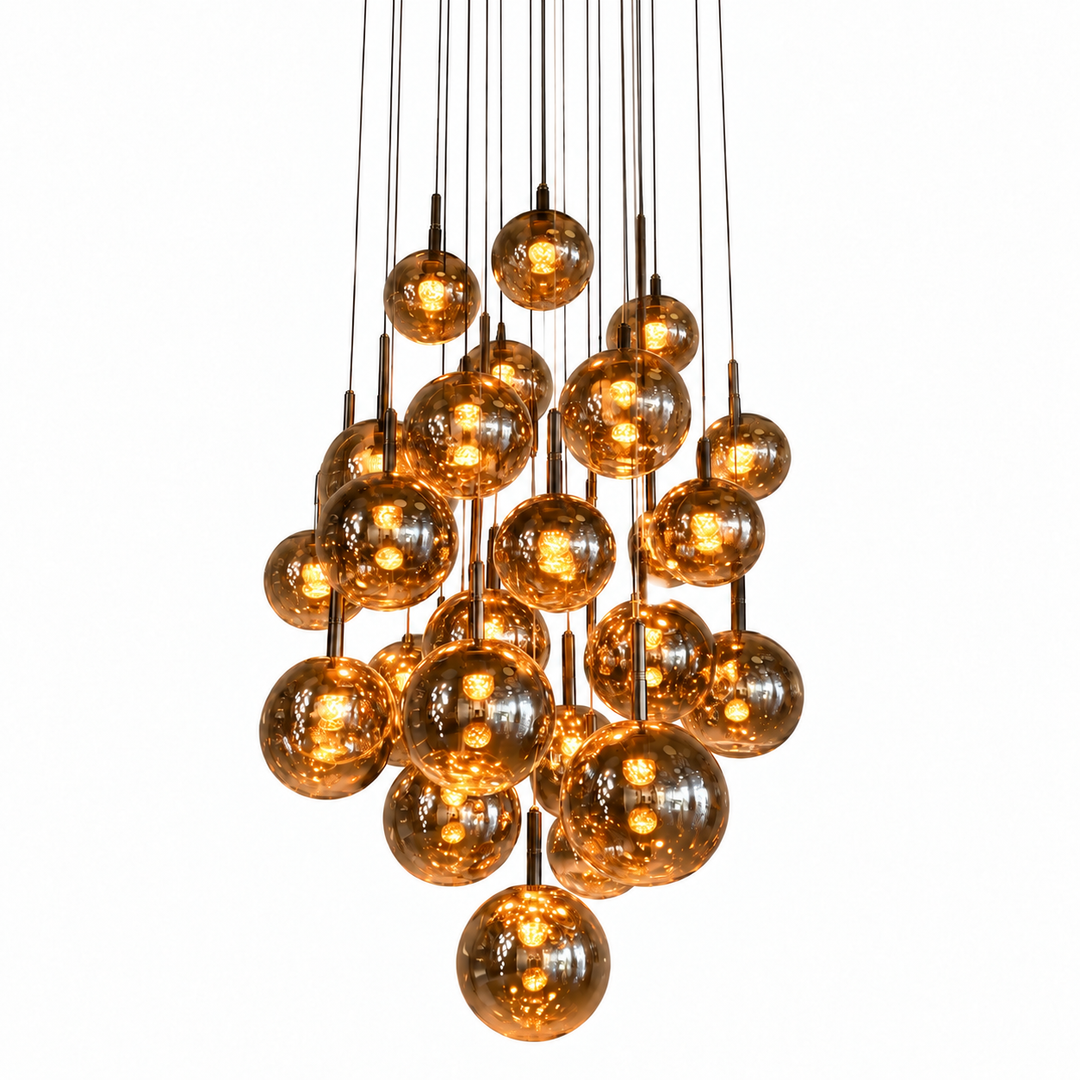 Chandelier with amber-tinted globes glowing on slender dark cables at staggered heights against a white background.