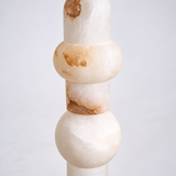 Floor lamp close-up shows cream alabaster rounded and cylindrical forms with brown veining against a pale background.