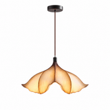 A modern pendant light with a dark metal canopy and rod, featuring a warm amber-tinted glass shade with a petal-like flared design, shown against a plain white background.
