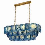 Linear chandelier with three tiers of textured blue glass, gold-toned chains and a matching ceiling canopy against a white background.
