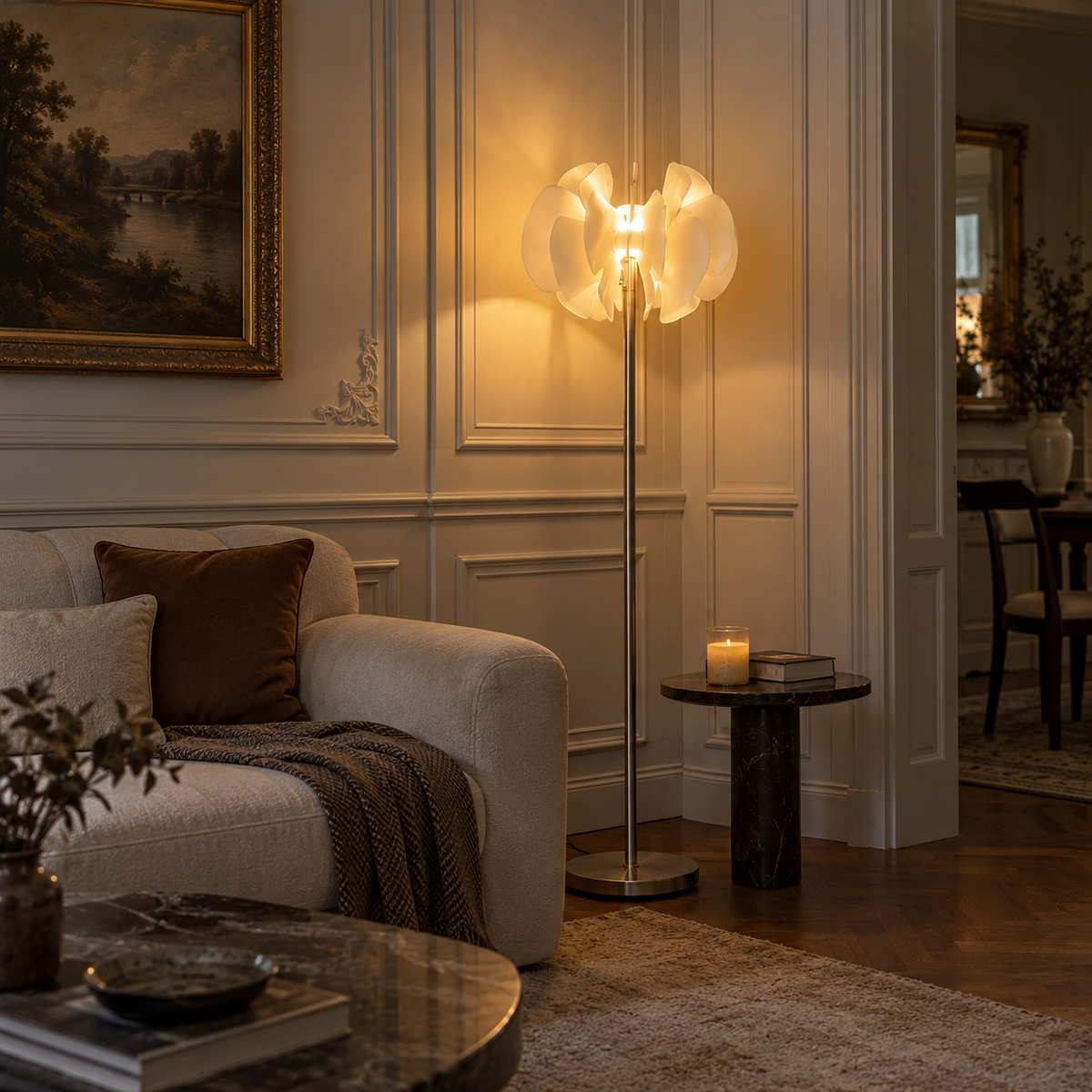 A modern floor lamp with a sculptural, cloud-like white shade and a slim metallic pole, glowing warmly in a classic European-style living room next to a beige sofa and a small side table.