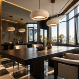 A modern dining room with a dark wood rectangular table, cream upholstered chairs, three round woven pendant lights, large windows, and a mirrored wall showing the room's depth.