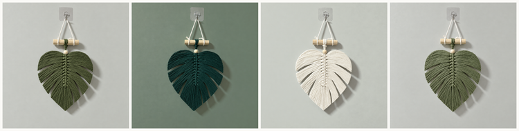Four hanging leaf-shaped wall decorations shown side by side in different color variations: dark green, deep teal, cream, and olive green, each suspended from a clear hook against a light gray background.