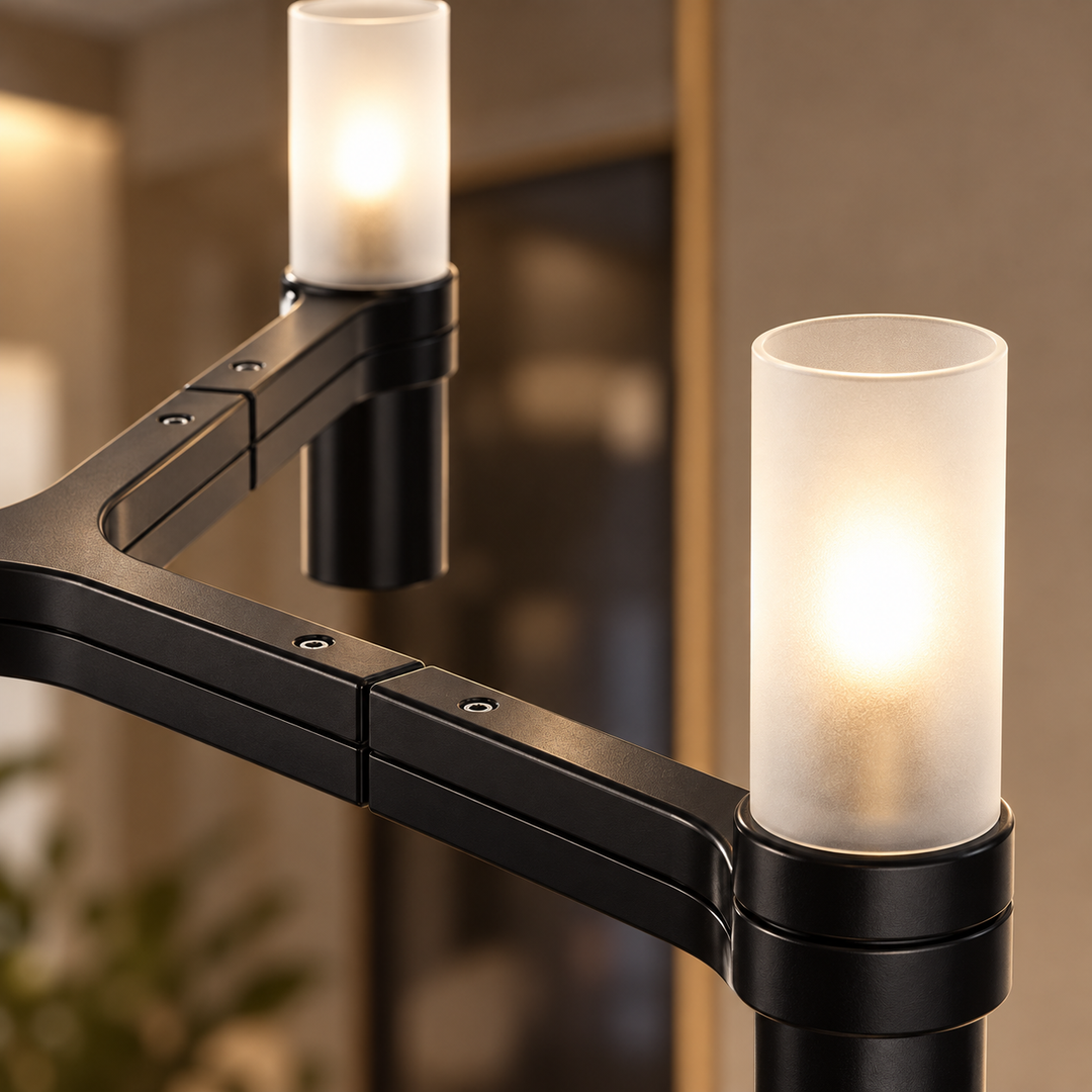 Chandelier close-up showing black metal arms and two illuminated frosted cylindrical glass shades against a softly blurred indoor background.