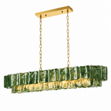 A linear chandelier with green rippled glass panels, gold-colored chains, and a matching ceiling canopy glows against a white background.