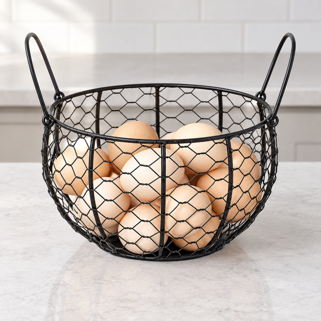 Black wire egg basket with raised side handles, holding eggs on a counter.