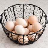 Eggs held inside the black hexagonal-wire basket.