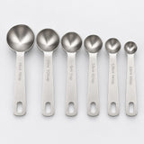Six separate stainless-steel measuring spoons with engraved capacities from 0.6 to 15 ml.